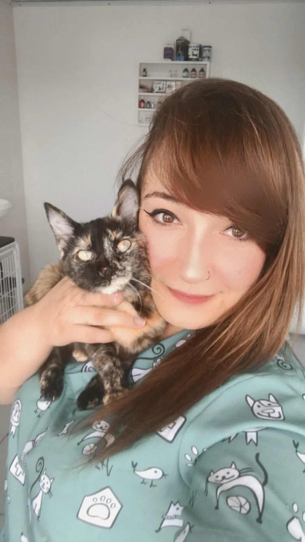 Dra Tay de pijama cirúrgico segurando uma gata tricolor no colo